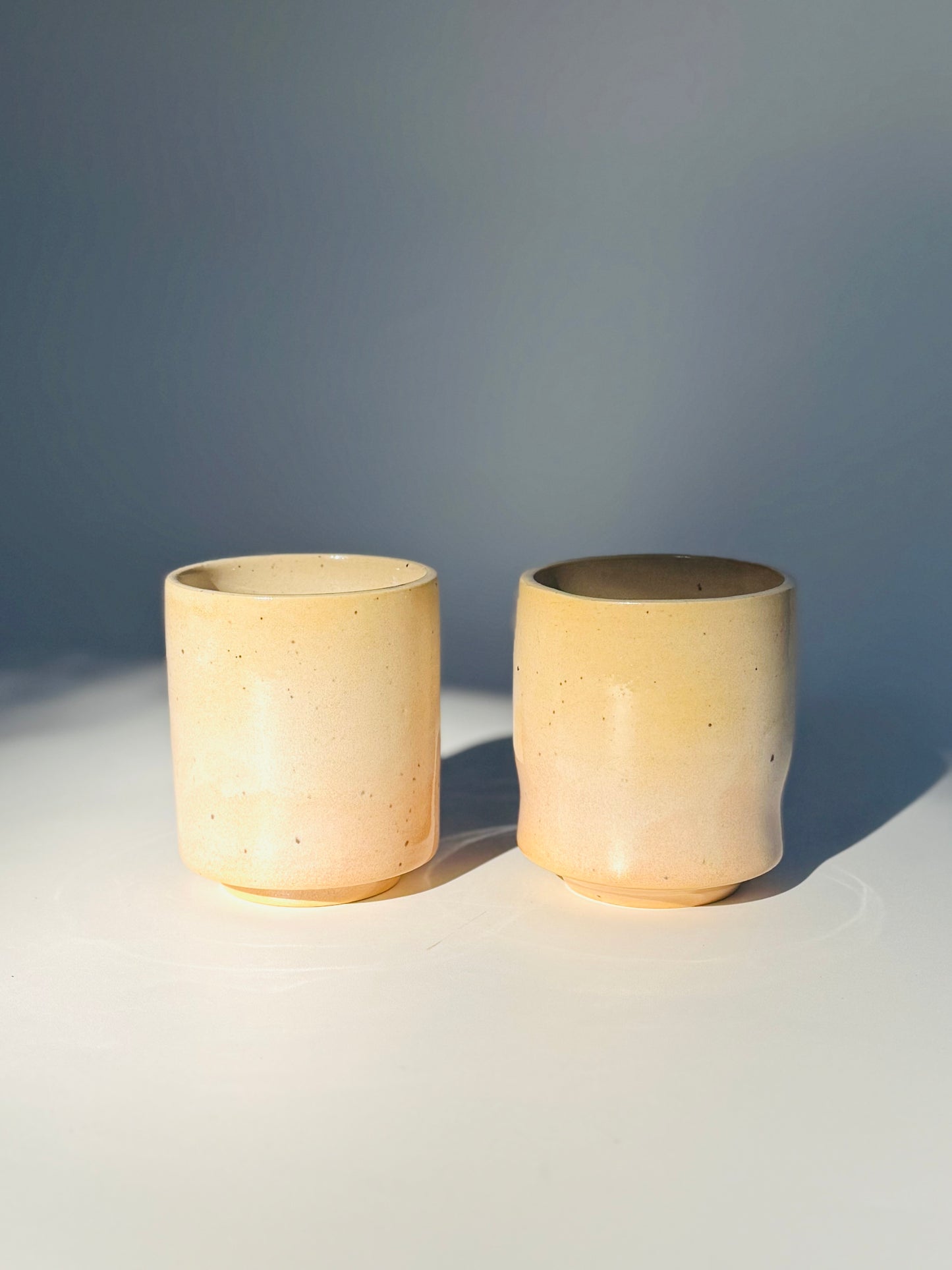 Straight on view of the unique Subtle Speckles Straight Cup (left) and the Subtle Speckles Grooved Cup (right) from Rita Strayer Ceramics Savannah. Perfectly tasteful little 6oz tumblers. Very faint speckle pattern appears throughout the clay mix.