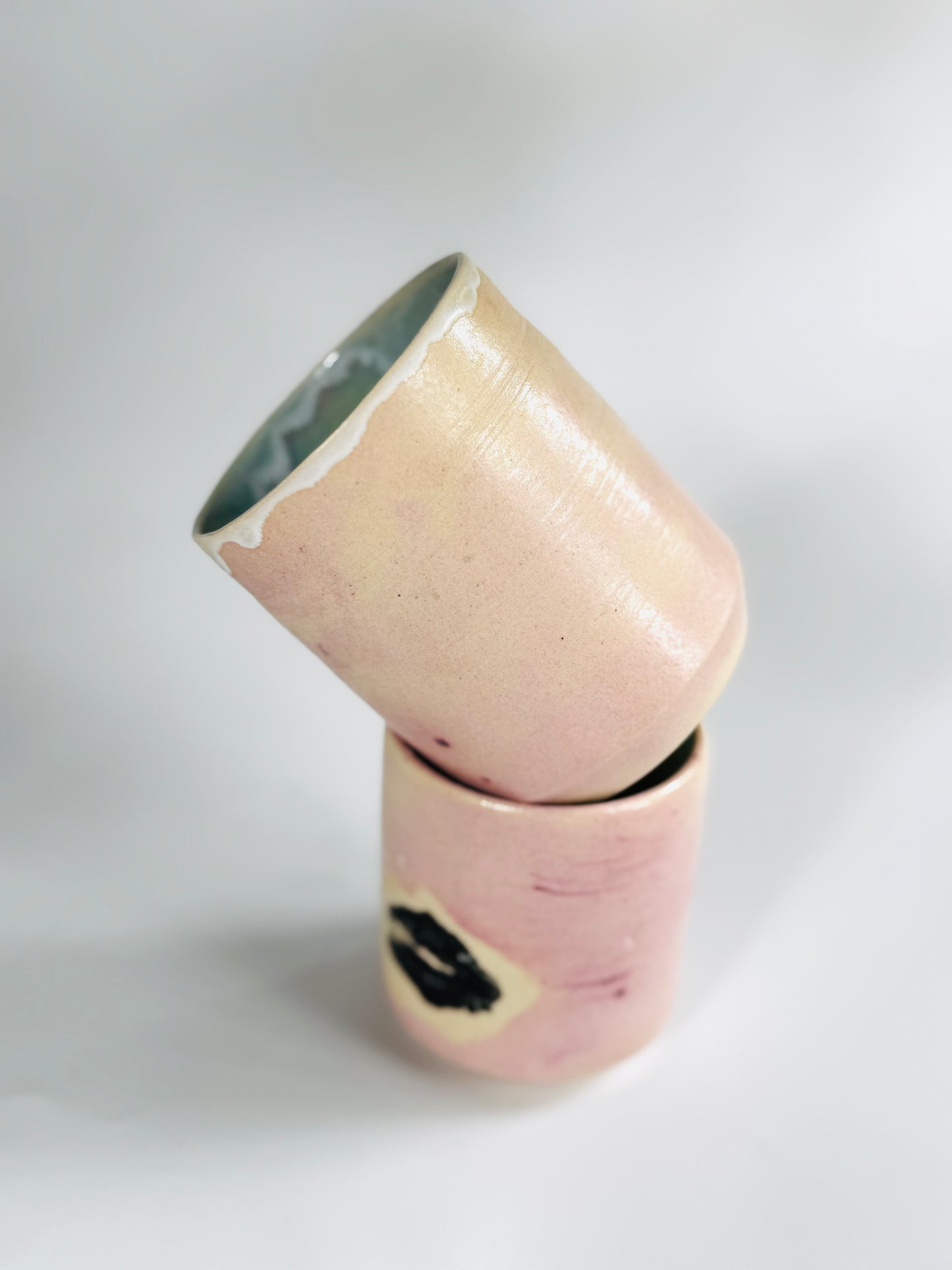 Dare I say tumbling view of the Large Kissy Cup Tumbler by Rita Strayer Ceramics of Savannah? This tumbler features Cascading flux rim, various sea foam interior and celadon bloom shads. Stoneware, microwavable, black lip design with pink dominant colors.