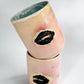 Playful tumbling view of the Large Kissy Cup Tumbler by Rita Strayer Ceramics of Savannah. Cascading flux rim, various sea foam interior and celadon bloom shads. Stoneware, microwavable, black lip design with pink dominant colors.