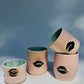 Set of four ceramic Kissy Cup Tumblers by Rita Strayer Ceramics of Savannah. This design features a cascading flux rim, various sea foam interior and celadon bloom shads. Stoneware, microwavable, black lip design with pink dominant colors and a blueish interior hue. Available in a variety of sizes.