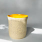 Ceramic tumbler mug with yellow interior on a black background
