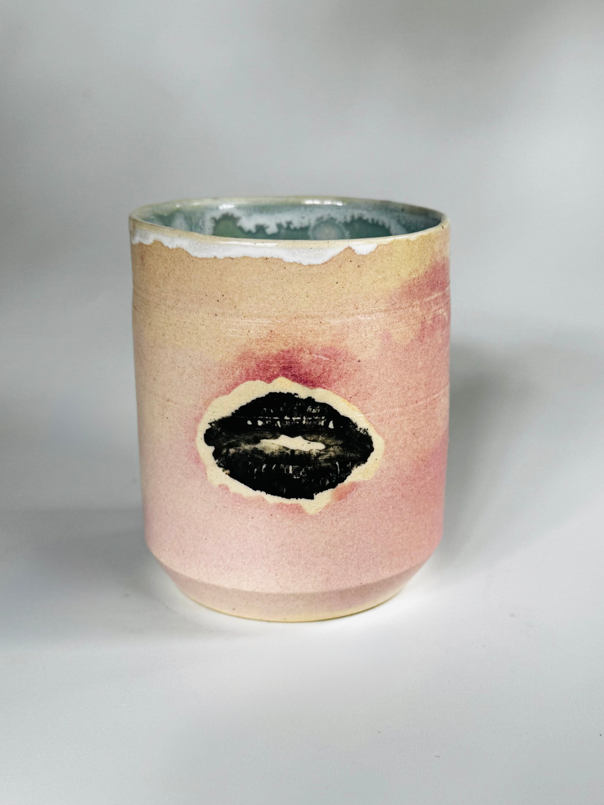 Head on view of the Large Kissy Cup Tumbler by Rita Strayer Ceramics of Savannah. Cascading flux rim, various sea foam interior and celadon bloom shads. Stoneware, microwavable.