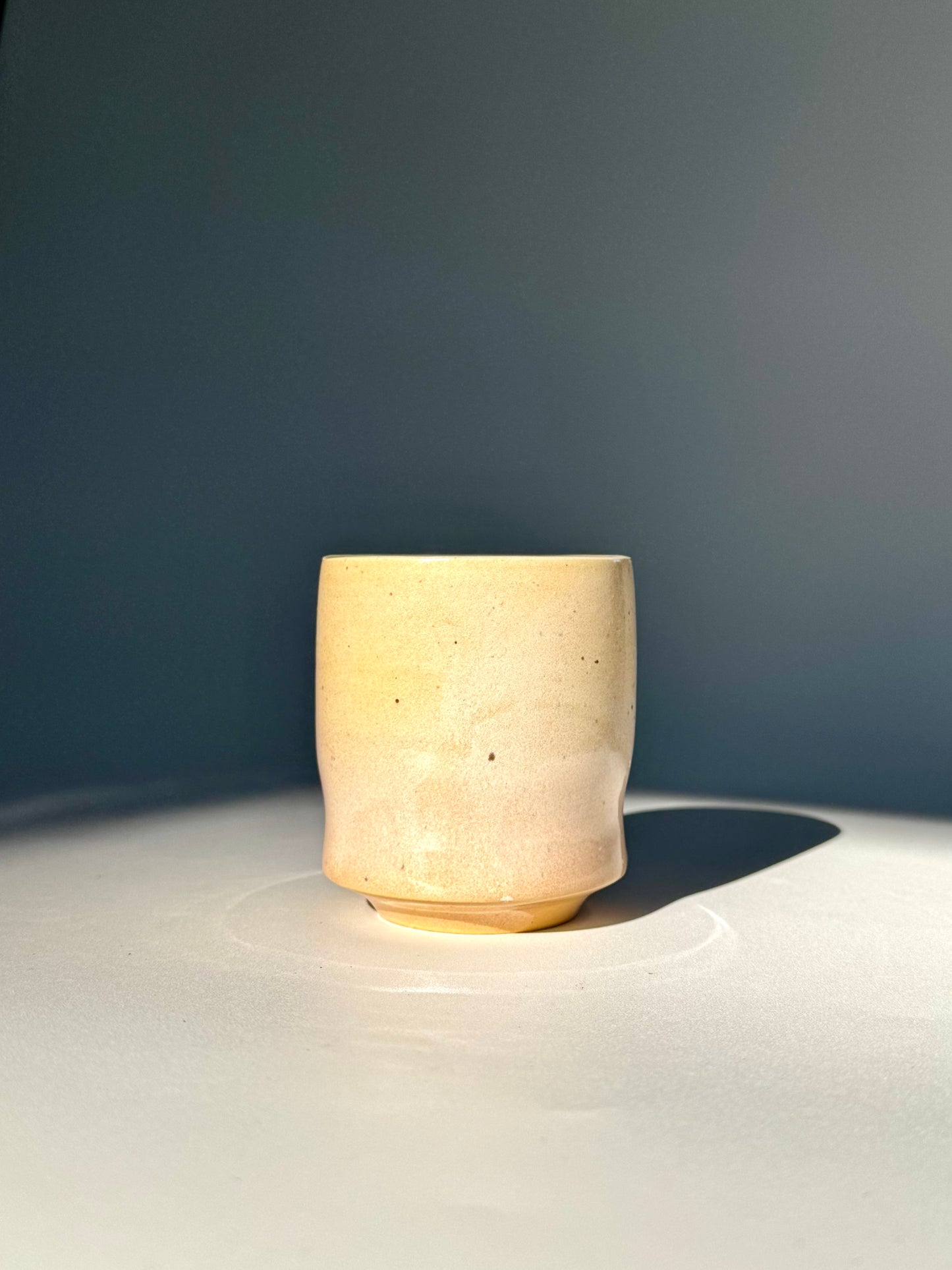 Distant upright view of the Unique Subtle Speckles Grooved Cup from Rita Strayer Ceramics Savannah. A tasteful little 6oz tumbler with grooves for small fingers. Faint speckle pattern.