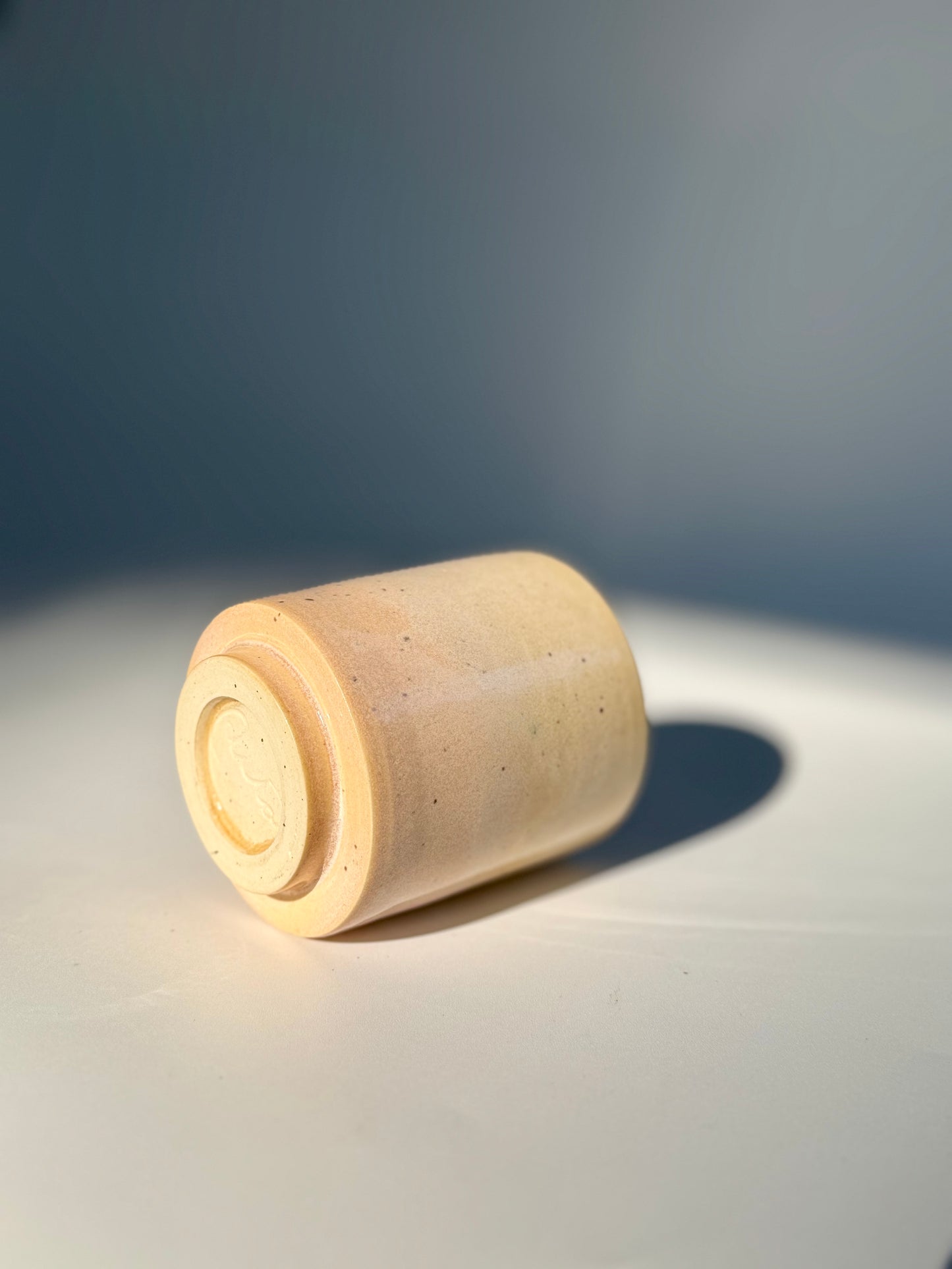 On its side view of the unique Subtle Speckles Straight Cup by Rita Strayer Ceramics Savannah. A tasteful little 6oz tumbler. Very faint speckle pattern appears throughout the clay mix.