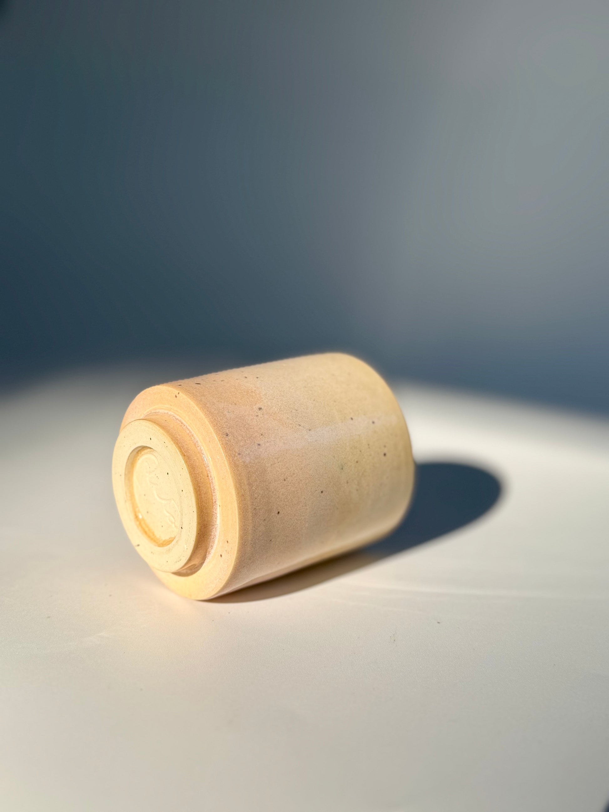 On its side view of the unique Subtle Speckles Straight Cup by Rita Strayer Ceramics Savannah. A tasteful little 6oz tumbler. Very faint speckle pattern appears throughout the clay mix.