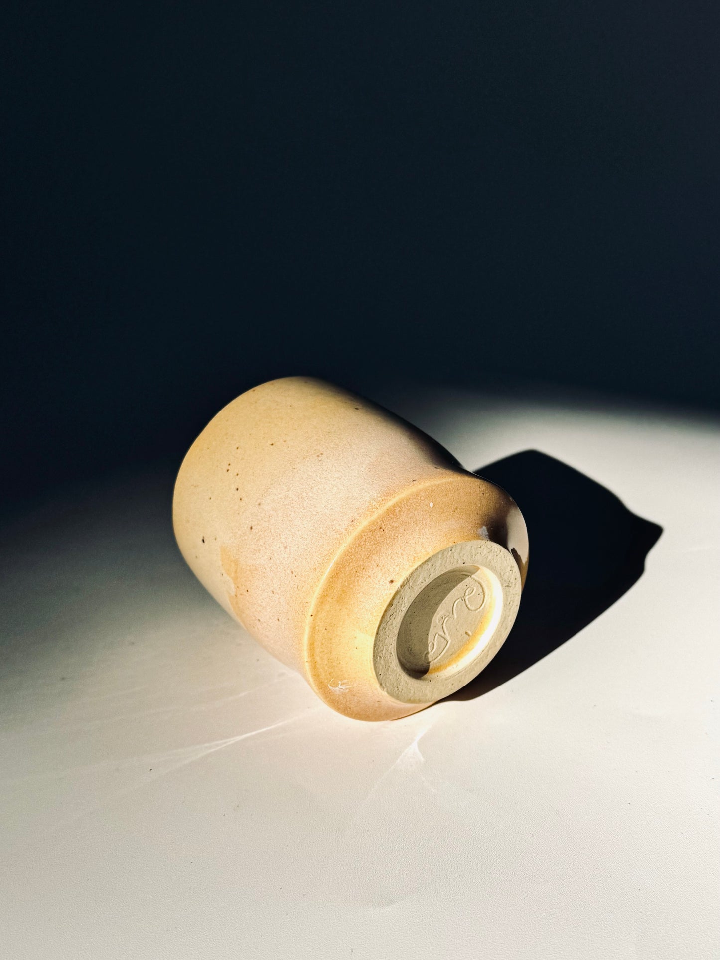 Overhead on its side view of the Unique Subtle Speckles Grooved Cup from Rita Strayer Ceramics Savannah. A tasteful little 6oz tumbler with grooves for small fingers. Faint speckle pattern.