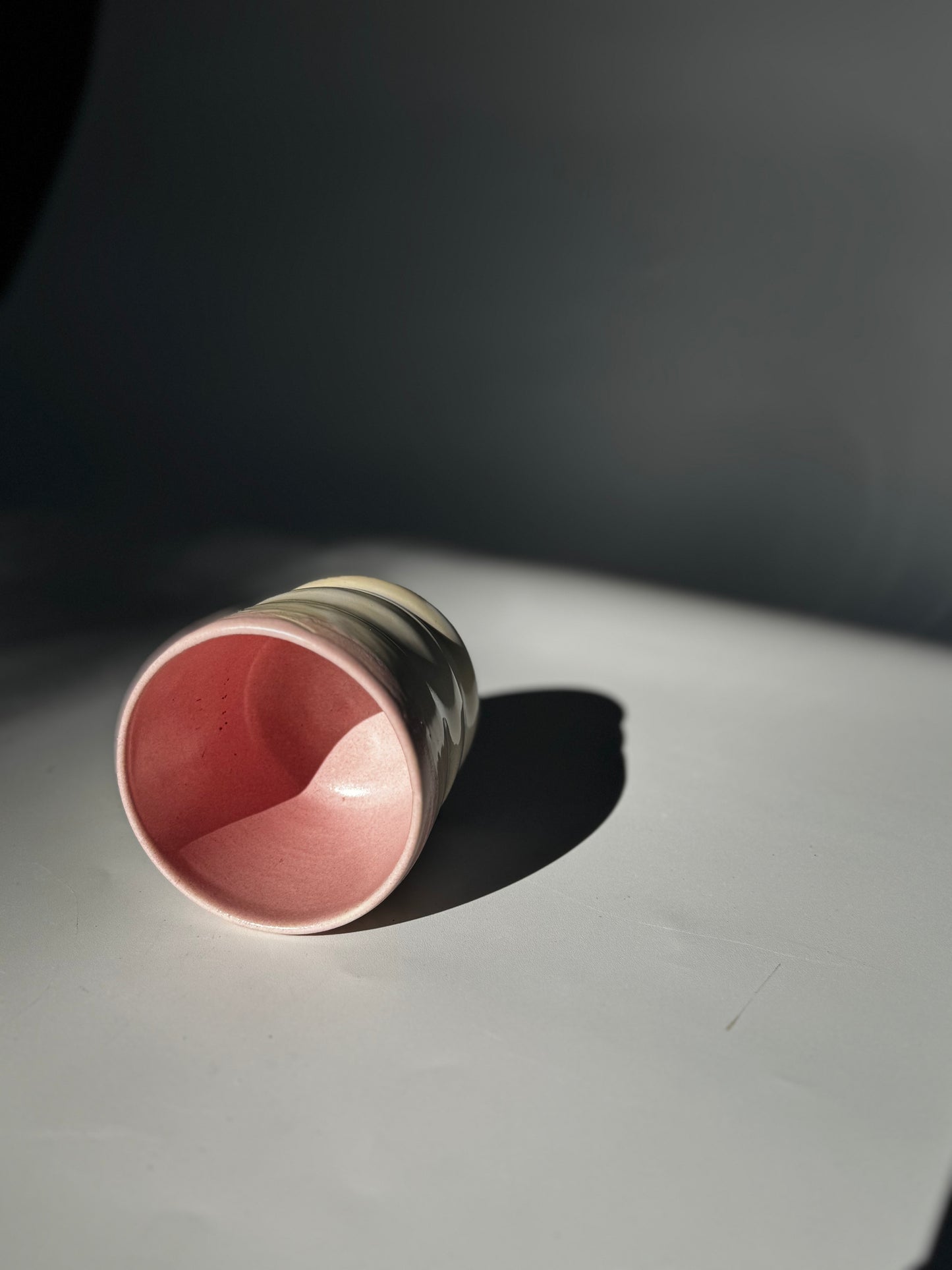 Side interior view of the Little Milk Cup tumbler design by Rita Strayer Ceramics of Savannah, GA. A tumbler with convenient finger grooves to accommodate little hands, sleepy hands, and slippery hands too. Two-tone pink and beige colouring.