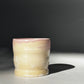 Straight ahead view of the Little Milk Cup tumbler design by Rita Strayer Ceramics of Savannah, GA. A tumbler with convenient finger grooves to accommodate little hands, sleepy hands, and slippery hands too. Two-tone pink interior, beige exterior colouring.