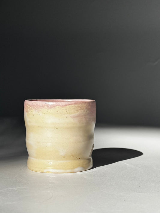 Straight ahead view of the Little Milk Cup tumbler design by Rita Strayer Ceramics of Savannah, GA. A tumbler with convenient finger grooves to accommodate little hands, sleepy hands, and slippery hands too. Two-tone pink interior, beige exterior colouring.