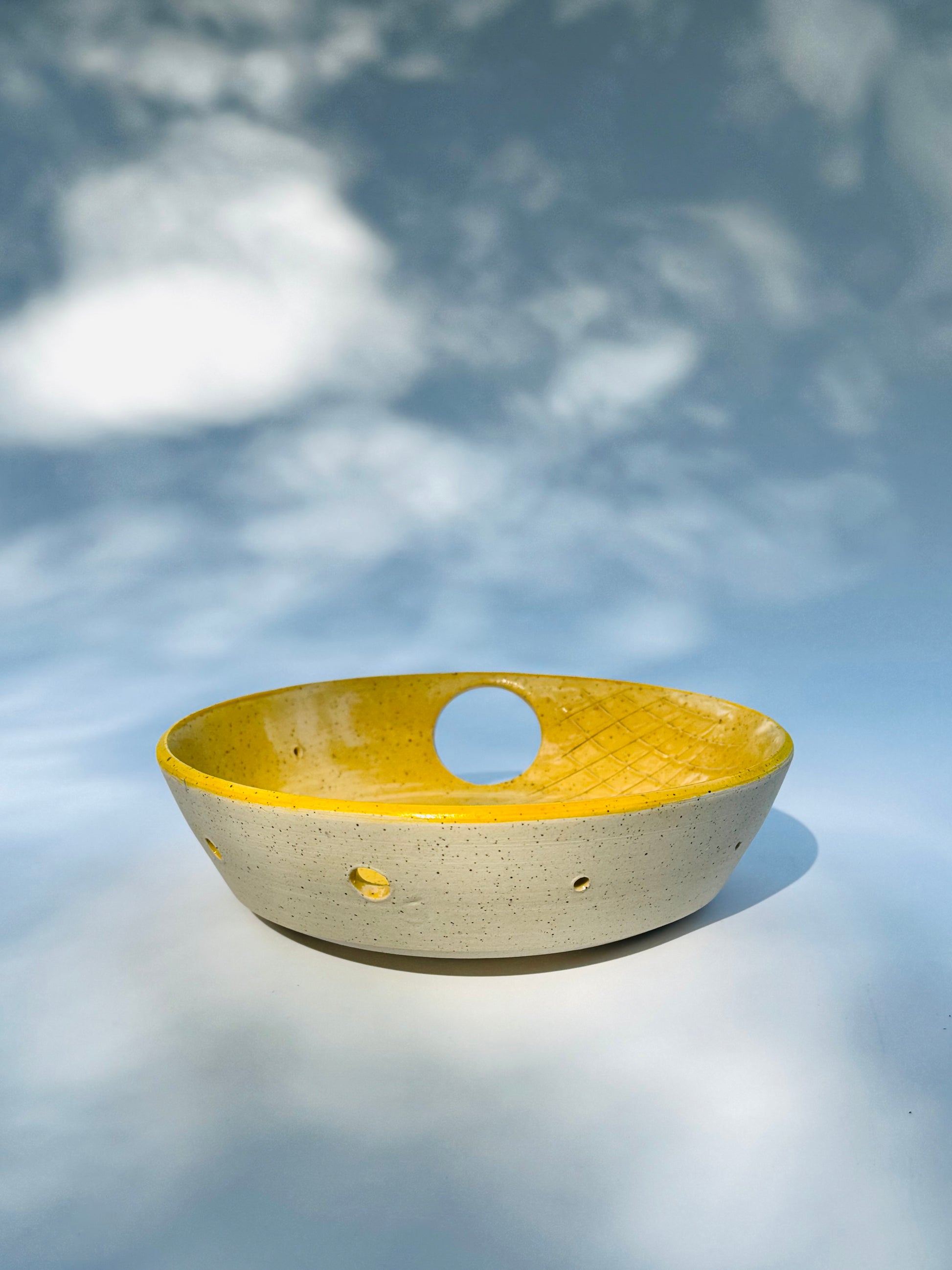 Straight ahead view of the one thumb hole herb stripper with garlic grater design in yellow from Rita Strayer Ceramics of Savannah. Easily strip leaves from your favorite herbs. Stoneware clay with celadon glaze. Thumb hole to allow for easier handling while stripping.